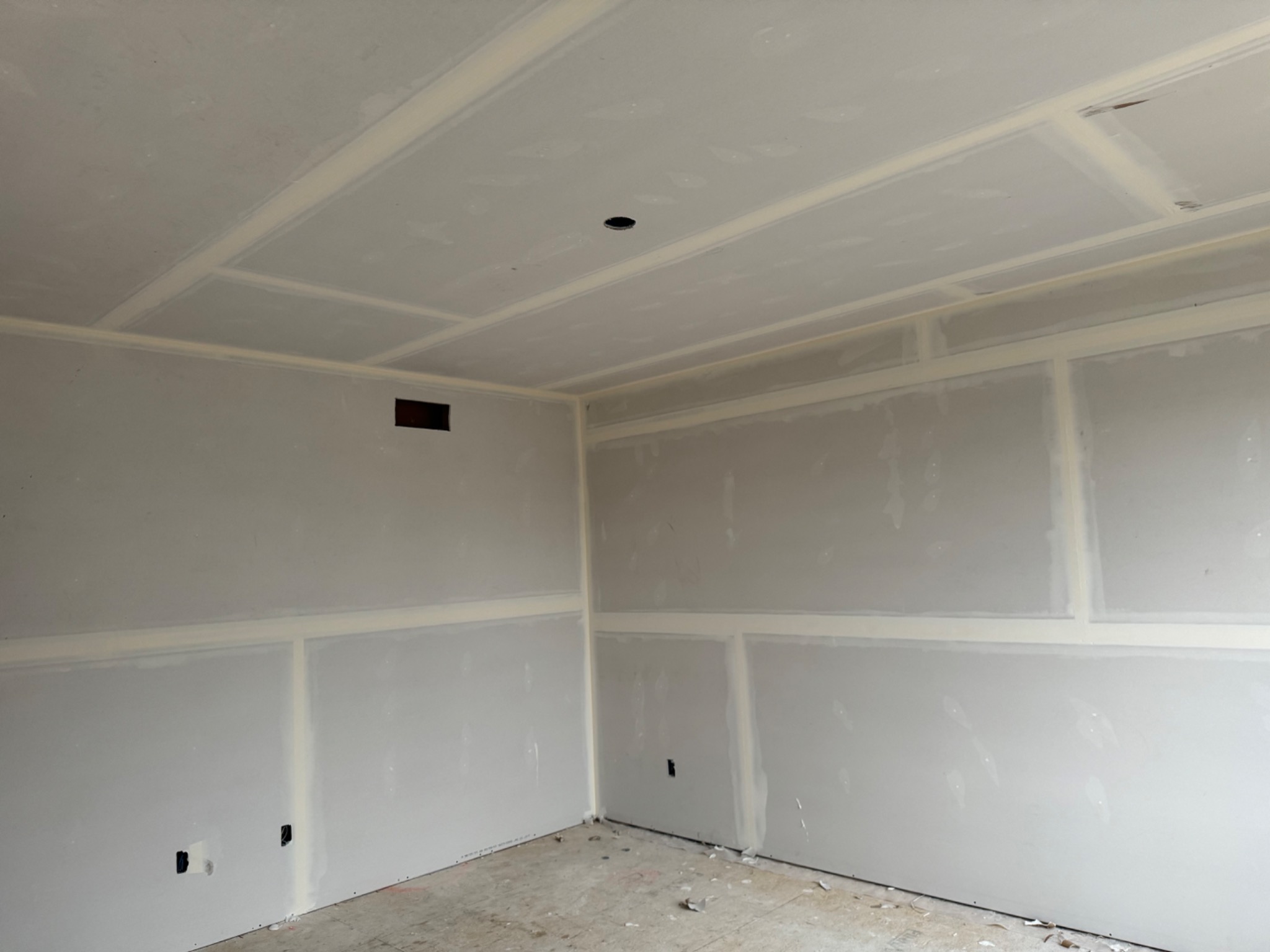 Drywall finishing in progress with clean ceiling and wall joints